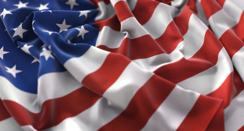 Close-up of a rippled American flag, with white stars on a blue field and red and white stripes.